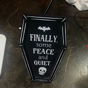 black coffin-shaped ‘peace + quiet’ sign